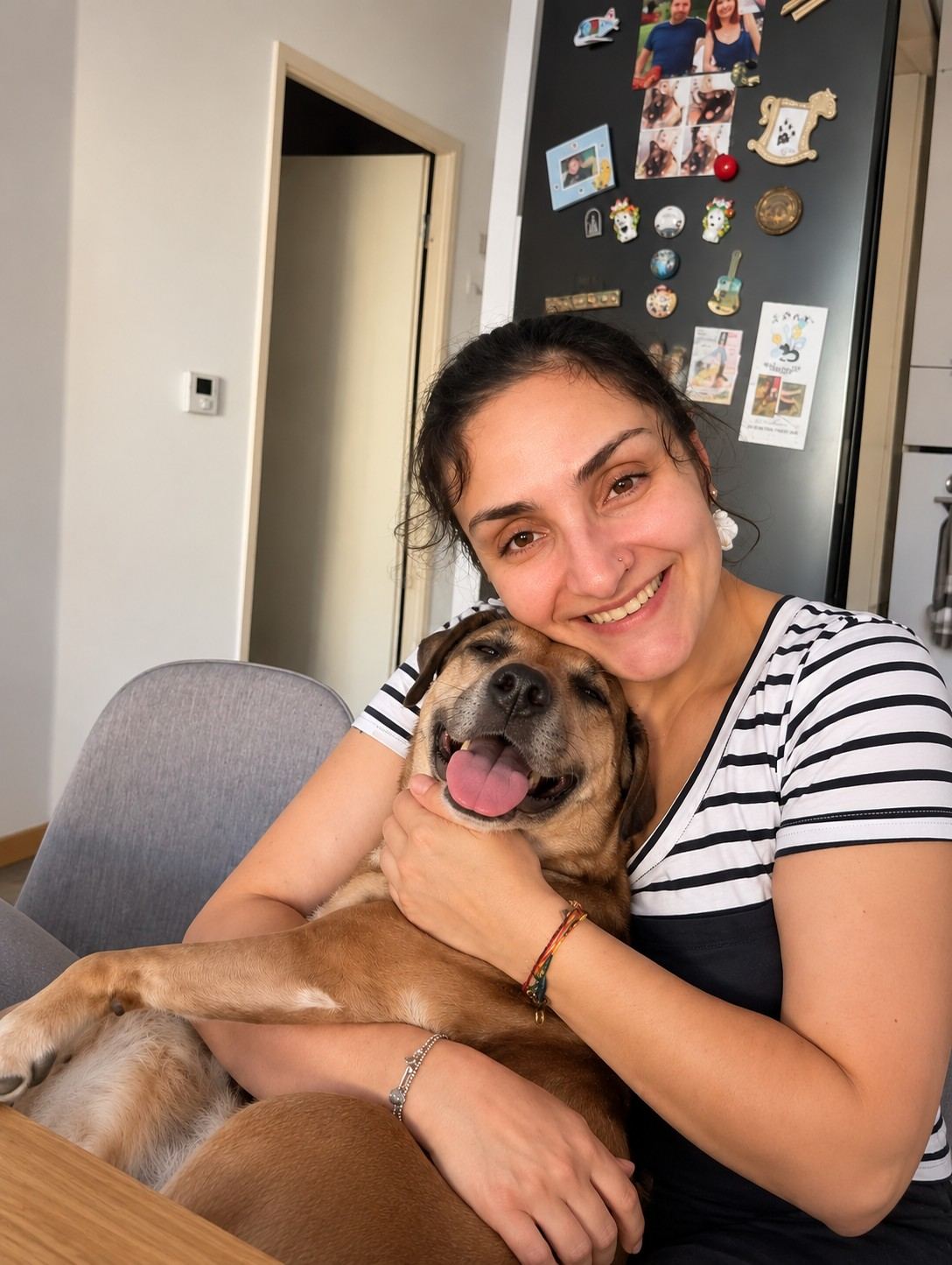 Une femme souriante serre un chien contre elle à la maison